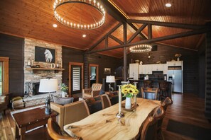 A spacious dining area with a long wooden table and chairs, a fireplace, and a kitchen in the background. - Dutton Chapel Lodge (Golconda No. 2 Precinct)