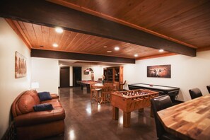 A cozy room with a pool table, foosball table, and a leather couch.