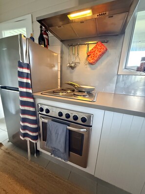 Ett kök med ett kylskåp i rostfritt stål, en gasspis, en ugn och köksredskap som hänger på väggen.
