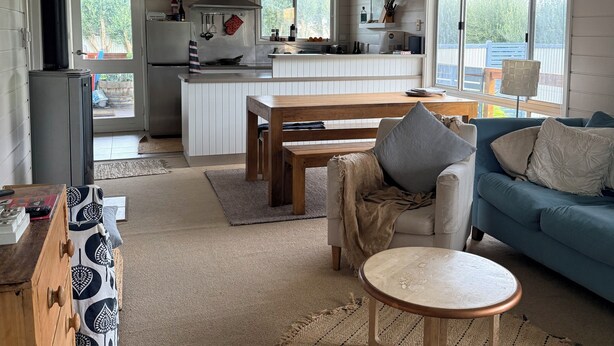 Eine moderne Küche mit Kochinsel, ein Essbereich mit Tisch und Stühlen sowie ein Wohnzimmer mit Sofa und Couchtisch.