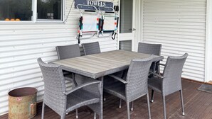 Eine überdachte Terrasse mit Tisch, Stühlen, einem Handtuchhalter und einem Mülleimer.