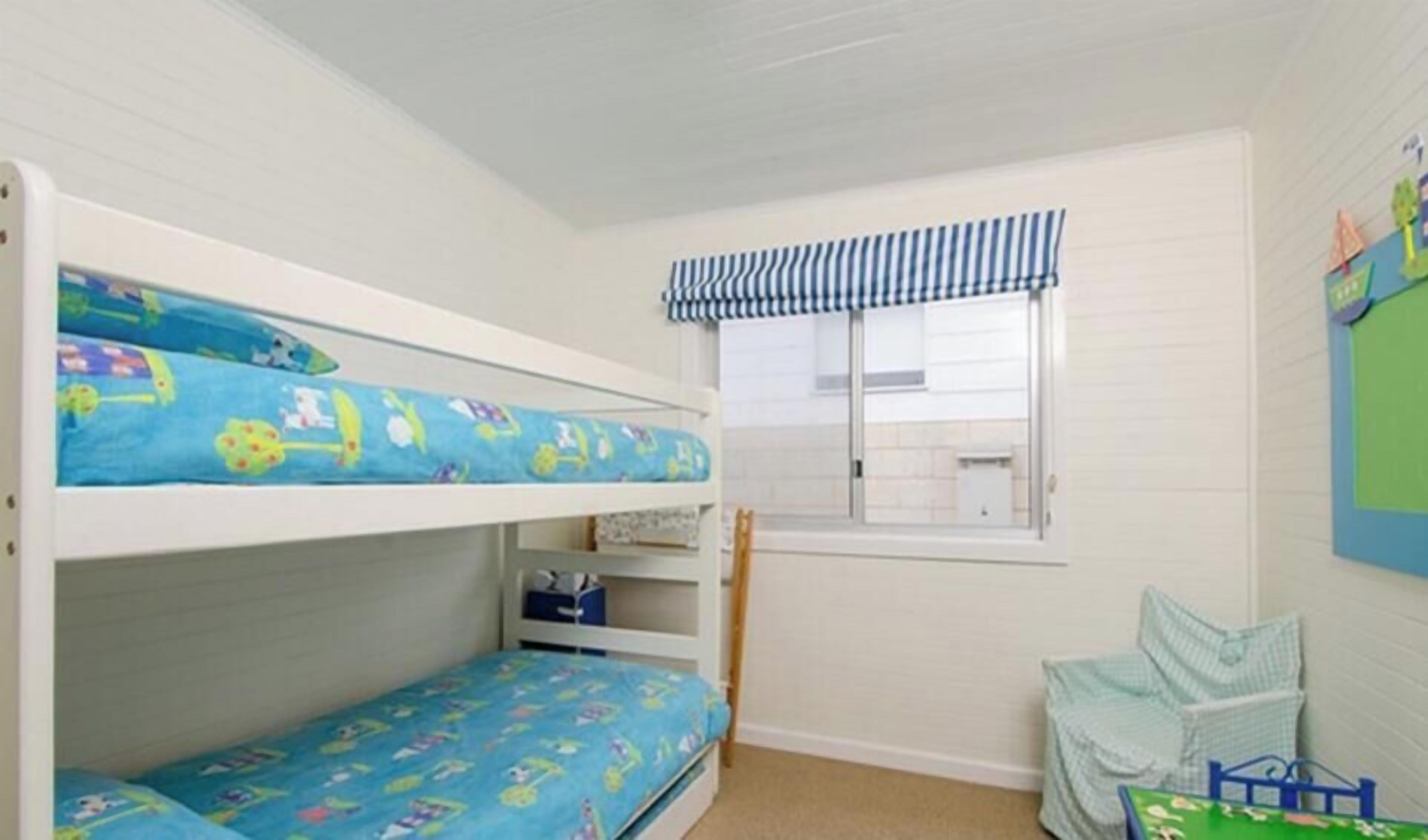 Ein Schlafraum mit Etagenbetten, einem Fenster und einem kleinen Tisch.