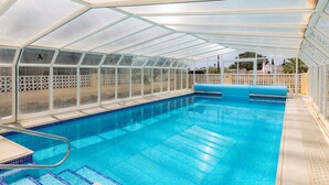 Ein Schwimmbad mit Glasdach, umgeben von einem weißen Zaun.