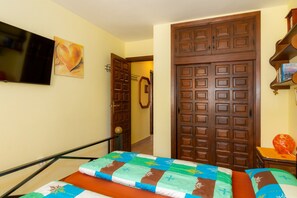 Ein Hotelzimmer mit einem Bett, einem an der Wand montierten Fernseher und einer Holztür.