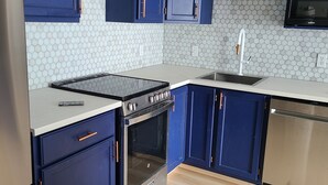 Une cuisine avec des armoires bleues, une cuisinière en acier inoxydable et un four à micro-ondes.