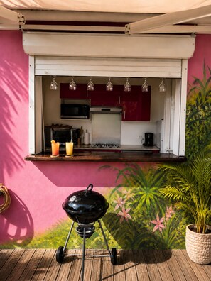 A kitchen with a microwave, oven, and coffee maker, a barbecue grill, and a potted plant. - Villa Orelia (Saint François)