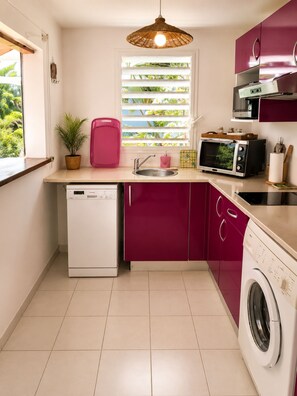 A compact kitchen with a dishwasher, microwave, and washing machine. - Villa Orelia (Saint François)