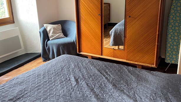 Un dormitorio con cama, armario, silla y ventana.