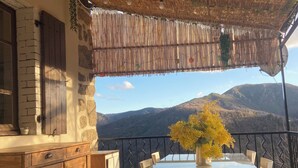 Un área de comedor al aire libre con mesa y sillas, un armario de madera y vistas a las montañas.