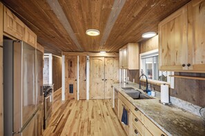 A wooden interior with a kitchen area, including a refrigerator, stove, and sink. - Walk to Private Beach: Bay-View Whidbey Island Gem (Oak Harbor)