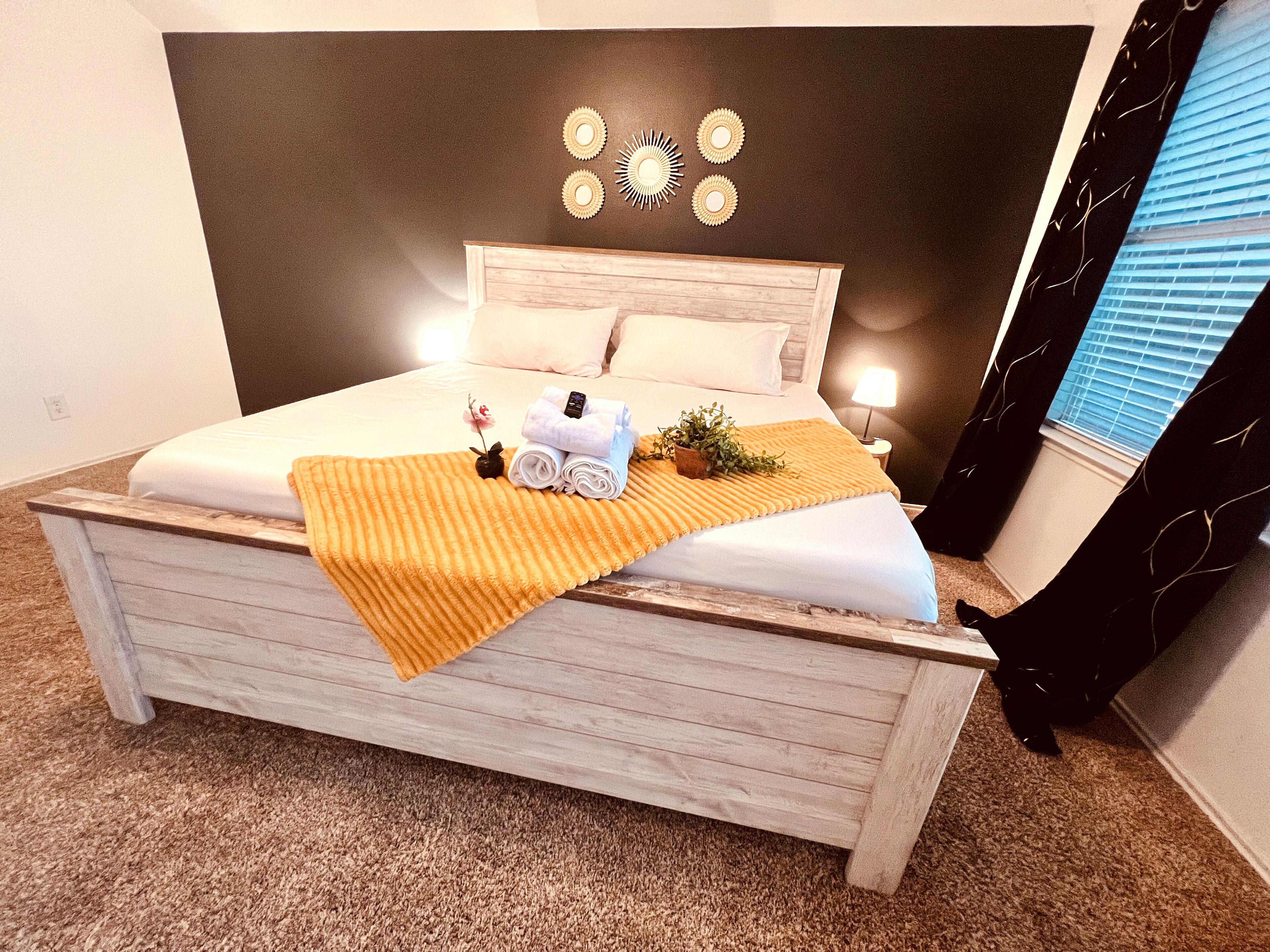 A neatly made bed with a headboard, a bedside lamp, and a small potted plant.