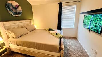 A bedroom with a bed, a television on the wall, and a window with blinds.