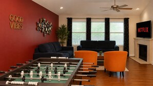 Una sala de estar con mesa de fútbol, dos sofás, televisión y chimenea.