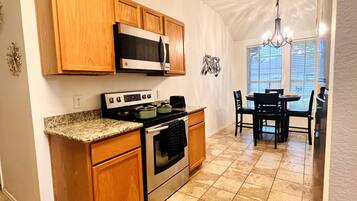 A kitchen with wooden cabinets, a stove, and a microwave.