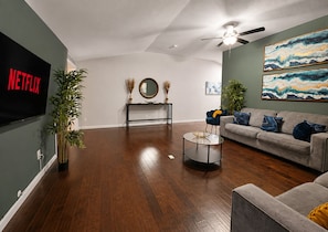 A living room with a flat-screen TV, a ceiling fan, a sofa, and a coffee table.