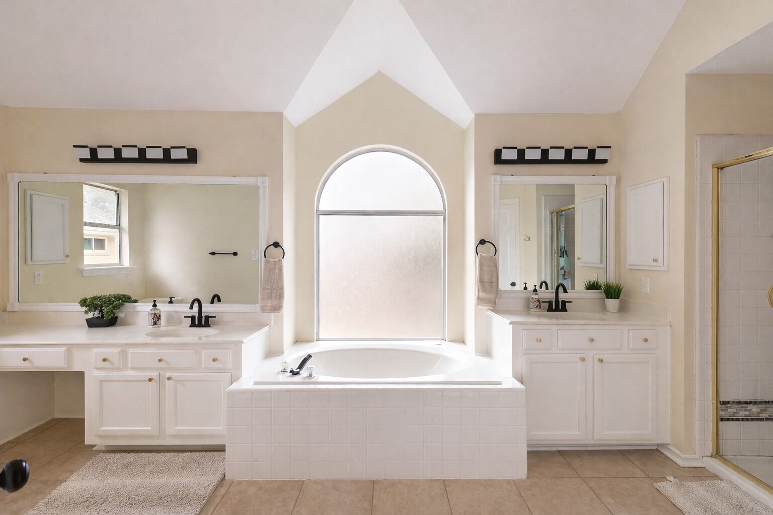 A spacious bathroom with a large bathtub, two sinks, and a walk-in shower.