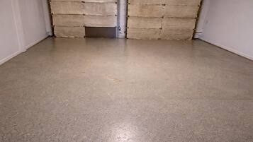 Una habitación con piso de concreto y dos puertas grandes cerradas.