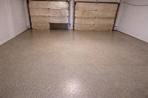Une pièce dotée d’un sol en béton et de deux grandes portes fermées.
