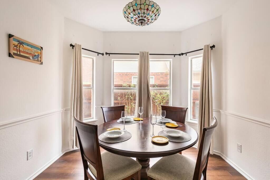 A dining area with a round table, chairs, and a chandelier.