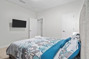 A bedroom with a bed, a flat-screen TV mounted on the wall, and two white doors. - Frisco 4BR | Crew, Team & Relocation Ready (Frisco)