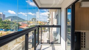 A balcony with a city view, a glass door, and a modern building facade. - Spacious Apartment Near Beto Carrero Lav0303 (Penha)