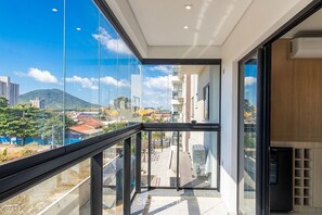 A balcony with a city view, a glass door, and a modern building facade. - Spacious Apartment Near Beto Carrero Lav0303 (Penha)