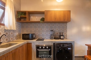 A compact kitchen with a dishwasher, oven, microwave, and coffee maker. - Studio w/ Balcony in Arraial D'ajuda Ipe0001 (Porto Seguro)