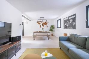 A modern living room with a TV, sofa, dining table, and decorative items.