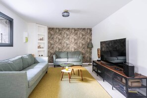 A modern living room with a sofa, a chair, a coffee table, a TV, and a bookshelf.