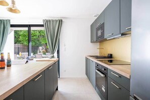A modern kitchen with grey cabinets, a wooden countertop, and a view of the outdoors.