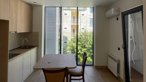 Una cocina moderna con comedor, ventanas amplias y vistas a edificios.