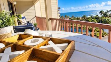 A wooden table with a white tablecloth, a wooden bench, and a view of the ocean and palm trees.