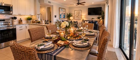 A dining area with a long table set for a meal, surrounded by wicker chairs.