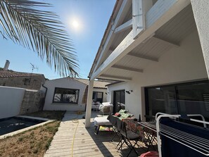 A patio with a pool, a dining area with a table and chairs, and a covered seating area. - House with a pool (Aigrefeuille-d'Aunis)