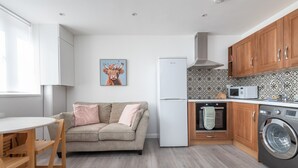 A modern kitchen with a refrigerator, oven, microwave, and washing machine. - Modern 2-bed Flat Near Hackney Central (London)
