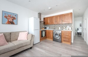 Eine kleine Küche mit Holzschränken, einer Waschmaschine und einem Kühlschrank.