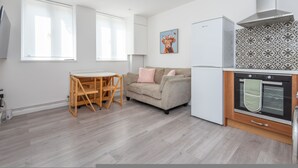 A modern kitchen with a built-in oven, a dining table with chairs, and a sofa. - Modern 2-bed Flat Near Hackney Central (London)