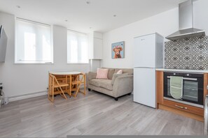 Eine moderne Küche mit Backofen, einem Esstisch mit Stühlen und einer Couch.