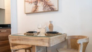 A dining area with a wooden table and chairs, a glass top, and a framed artwork on the wall. - Marina Escape Steps from JBR Beach (Dubai)