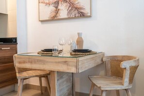 A dining area with a wooden table and chairs, a glass top, and a framed artwork on the wall. - Marina Escape Steps from JBR Beach (Dubai)
