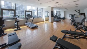 A gym with exercise equipment, large windows, and a wooden floor. - Marina Escape Steps from JBR Beach (Dubai)