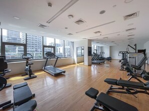 A gym with exercise equipment, large windows, and a wooden floor. - Marina Escape Steps from JBR Beach (Dubai)