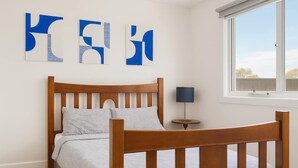 Ein Schlafzimmer mit einem Holzbett, einem Nachttisch mit Lampe und abstrakter Wandkunst.
