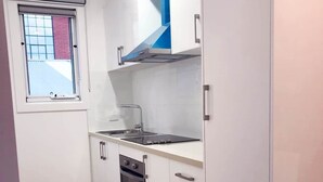 Eine kleine Küche mit Fenster, einem Backofen und einem Spülbecken.