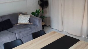 Ein modernes Wohnzimmer mit einem grauen Sofa, einem Holzesstisch und einem Deckenventilator.