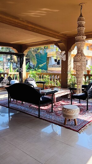 A covered outdoor seating area with a patterned rug, a decorative column, and a view of the surrounding buildings. - Hill view apartment (Ashwem)