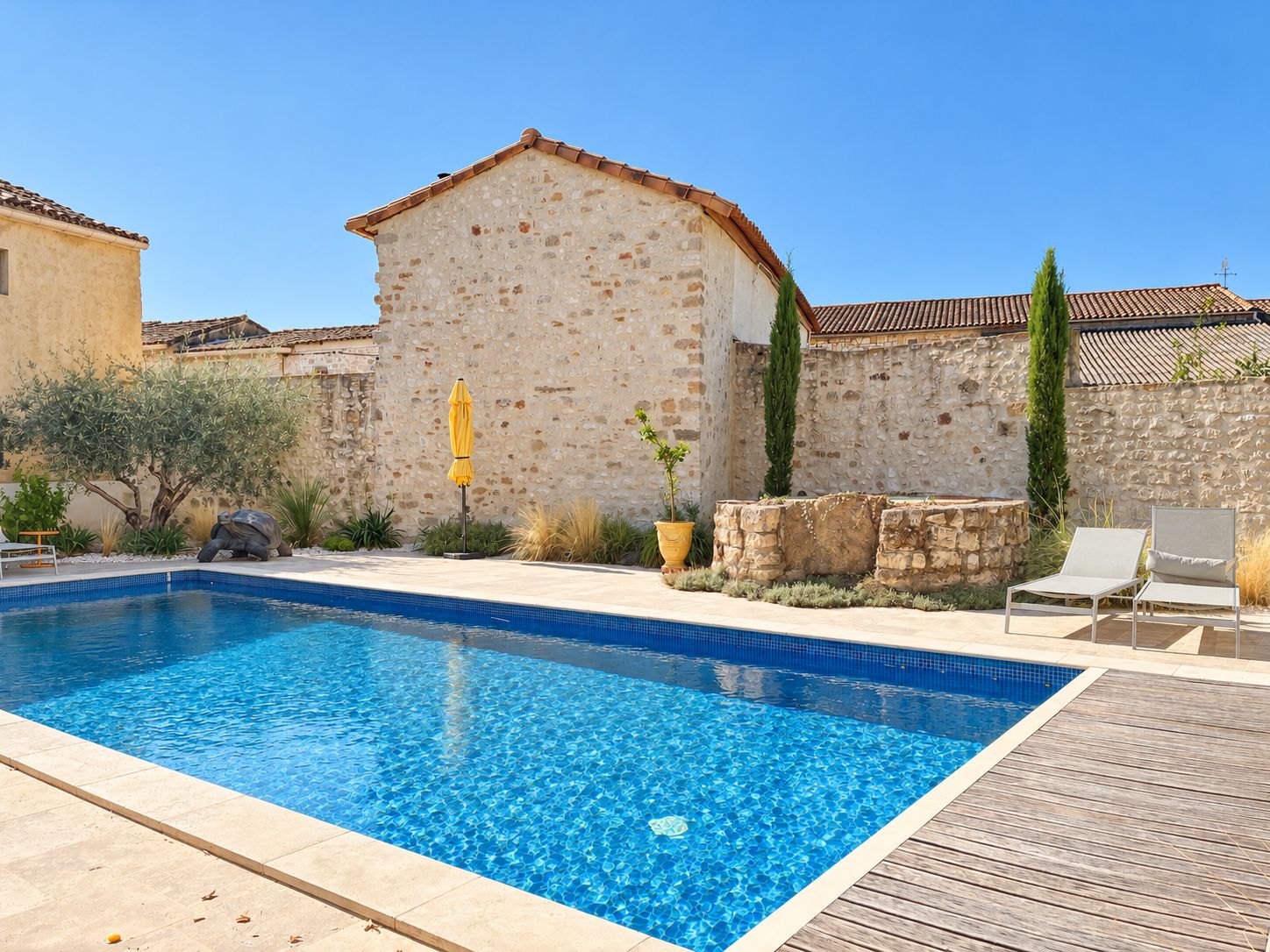 A swimming pool with a stone wall and a wooden deck.