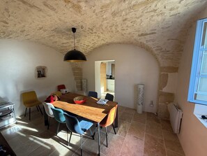 A dining area with a wooden table, chairs, and a hanging light fixture. - Authentic farmhouse with a pool, 10 minutes from Uzès, for 8 people (Garrigues-Sainte-Eulalie)