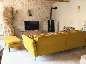 Ein Wohnzimmer mit Steinsandsteinwand, einem Fernseher, einer Couch und einem Kamin.
