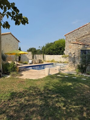 A stone building with a swimming pool, outdoor seating, and a clear sky. - Authentic farmhouse with a pool, 10 minutes from Uzès, for 8 people (Garrigues-Sainte-Eulalie)